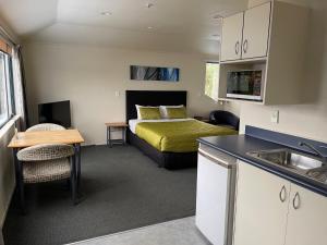 a bedroom with a bed and a kitchen with a sink at Bassingers Motor Lodge in Levin