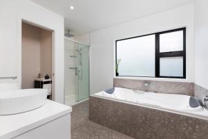 a white bathroom with a tub and a window at Oakura Beach Front Apartments in Oakura