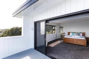 een slaapkamer met een bed en een glazen schuifdeur bij Oakura Beach Front Apartments in Oakura