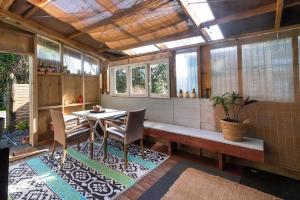 a dining room with a table and chairs and windows at The Little House Tutukaka in Tutukaka