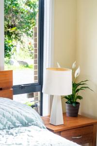 a lamp sitting on a table next to a bed at The Little House Tutukaka in Tutukaka