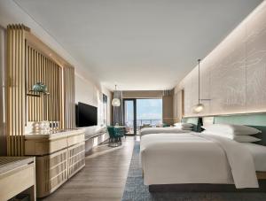 a hotel room with three beds and a television at Qinhuangdao Marriott Resort in Qinhuangdao