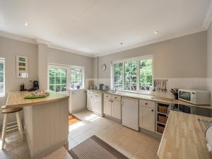 a large kitchen with white cabinets and white appliances at Blackberry Lodge in Ashburton
