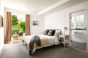 a white bedroom with a bed and a window at The Studio in Pevensey