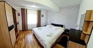 a bedroom with a bed with white sheets and a window at apartament BEST VIEW in Buşteni +2 photos