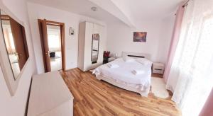 a bedroom with a white bed and a wooden floor at apartament BEST VIEW in Buşteni