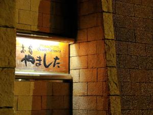 un panneau sur un mur de briques dans un bâtiment dans l'établissement Oyado Yamashita, à Kanazawa