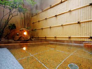 a rain soaked room with a wall and a stone floor at Oyado Yamashita in Kanazawa