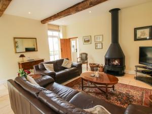 a living room with a leather couch and a fireplace at Old Coach House in Shrawardine