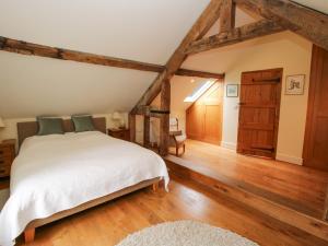 een slaapkamer met een wit bed en houten vloeren bij Old Coach House in Shrawardine