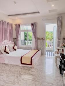 Godiva Villa Phu Quoc في فو كووك: غرفة نوم بيضاء مع سرير كبير ونوافذ