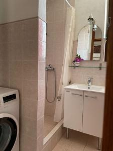 a bathroom with a shower and a sink and a washing machine at Apartment Željka-25m from beach in Zaglavice