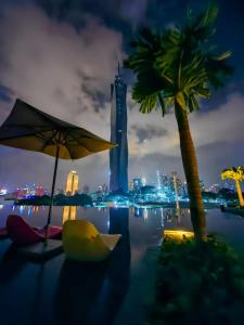 a pool with a palm tree and a city at night at ASTRA at Opus Residences Kuala Lumpur in Kuala Lumpur