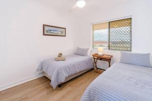 1 dormitorio con 2 camas y ventana en Pippi Beach Penthouse en Yamba