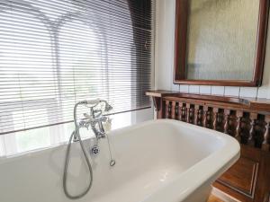 een badkuip met douche in een badkamer bij Capel Mawr in Llanrug +32 foto's