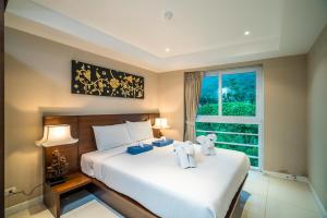 Kata Ocean View condominium by Lofty في شاطئ كاتا: غرفة نوم مع سرير مع دبتين عليه