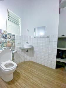 a white bathroom with a toilet and a sink at Aquamarine Weligama in Weligama