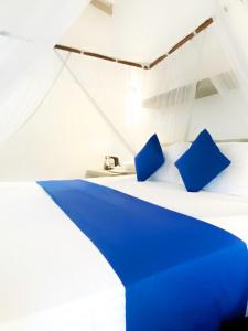 a white bed with blue pillows in a room at Aquamarine Weligama in Weligama