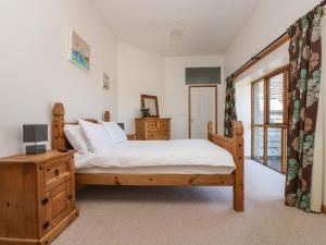 a bedroom with a bed and a wooden dresser at The Shippon in Bude