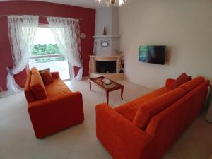 a living room with two orange couches and a fireplace at Margaret's Guest House in Mesopotam