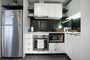 a kitchen with white cabinets and a stainless steel refrigerator at ‘Sunrise on Aura’ Apartment with stunning views. in Melbourne