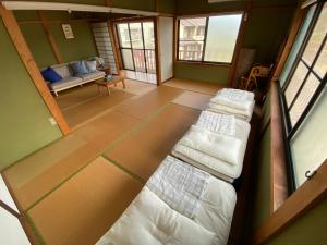 熊野市にあるアタシカデイズ Kumano Kodo Private Beach Houseのベッド3台とソファが備わる部屋