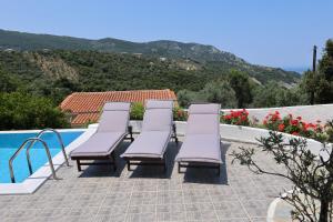 Un grupo de tumbonas junto a una piscina. en VILLA LIA-SKIATHOS-PRIVATE POOL-, en Skiathos