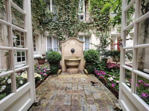 - un jardin avec une fontaine au milieu d'un bâtiment dans l'établissement Le Relais Médicis, à Paris