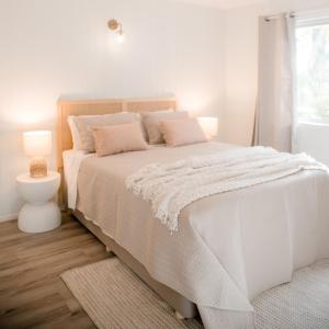 a white bedroom with a bed with a white blanket at Malie - By The Sea in Torquay