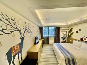 a bedroom with a bed and a tree on the wall at Morn Sun Hotel in Changhua County
