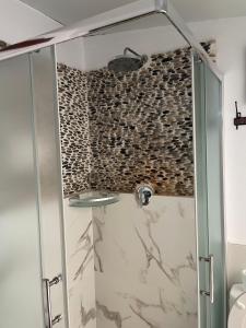 y baño con ducha y pared de piedra. en Casa Ojala, en Alicante