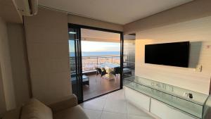 a living room with a television and a view of the ocean at Beira Mar Fortaleza Landscape Luxo in Fortaleza