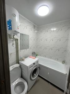 a bathroom with a toilet and a washing machine at Однокомнатная квартира в центре города in Balqash