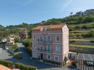 a pink house in a town with hills in the background at Appartamento Melograno "A Casa Felice" in Pietra Ligure