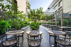 an outdoor patio with tables and chairs and plants at Publica Isrotel, Autograph Collection in Herzelia 