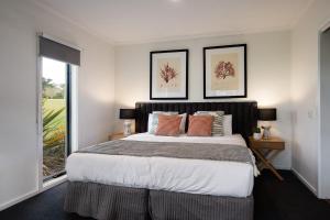 a bedroom with a large bed with two pictures on the wall at Manna Gums in Daylesford