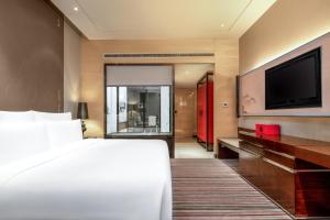 a hotel room with a bed and a flat screen tv at Le Meridien Chongqing Nan'an in Chongqing