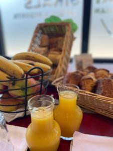 two glasses of orange juice next to a basket of bread at The Originals Access, Hôtel Arum, Remiremont (Inter-Hotel) in Remiremont