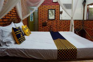 een slaapkamer met een groot bed met gele en blauwe kussens bij SPOT ON 92698 Holy Homestay in Banyuwangi