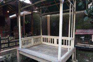een veranda van een huis met een houten bank bij SPOT ON 92698 Holy Homestay in Banyuwangi