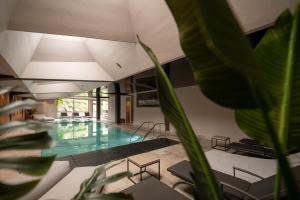 een huis met een zwembad met stoelen en een plant bij Hotel Pollinger in Merano