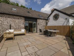 a patio with a table and chairs and a building at Pen-Croeslan Bach in Crickhowell