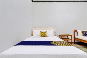 a bedroom with a white bed with yellow and blue pillows at SPOT ON 92623 Mw 46 Guesthouse in Yogyakarta