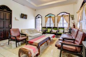a living room with leather furniture and windows at SPOT ON 92623 Mw 46 Guesthouse in Yogyakarta
