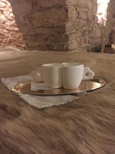 twee koffiekopjes en een bord op een tafel bij Locus Amoenus Luxury rooms in Terlizzi