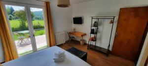 Cette chambre comprend un lit, une fenêtre et une table. dans l'établissement Le Jardin de Moulis - Maison d'hôtes au pied des Pyrénées, Ariège, Saint Girons, à Moulis