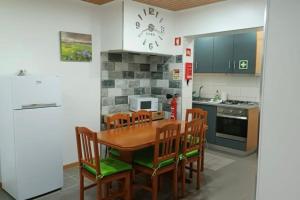 a kitchen with a wooden table and wooden chairs at Cantinho do Cruzeiro Lajes in Lajes