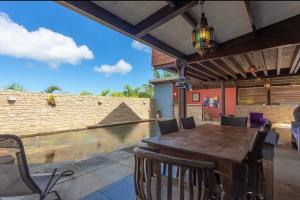 uma sala de jantar exterior com uma mesa de madeira e cadeiras em Villa Hermès chambre en suite parentale em Saint-Pierre