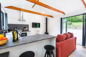 uma cozinha e sala de estar com um sofá vermelho em The Cabin in the Tamar Valley. em Gunnislake