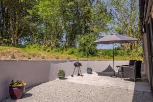 a patio with a table and an umbrella at The Cabin in the Tamar Valley. in Gunnislake
